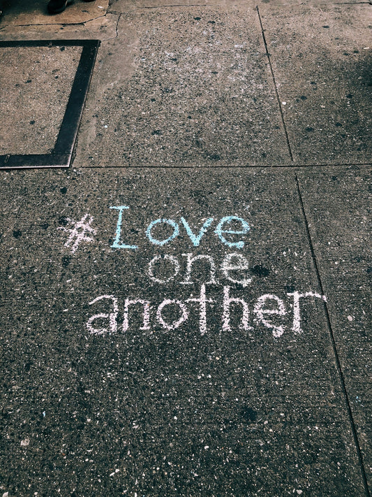 love one another chalk written on concrete floor