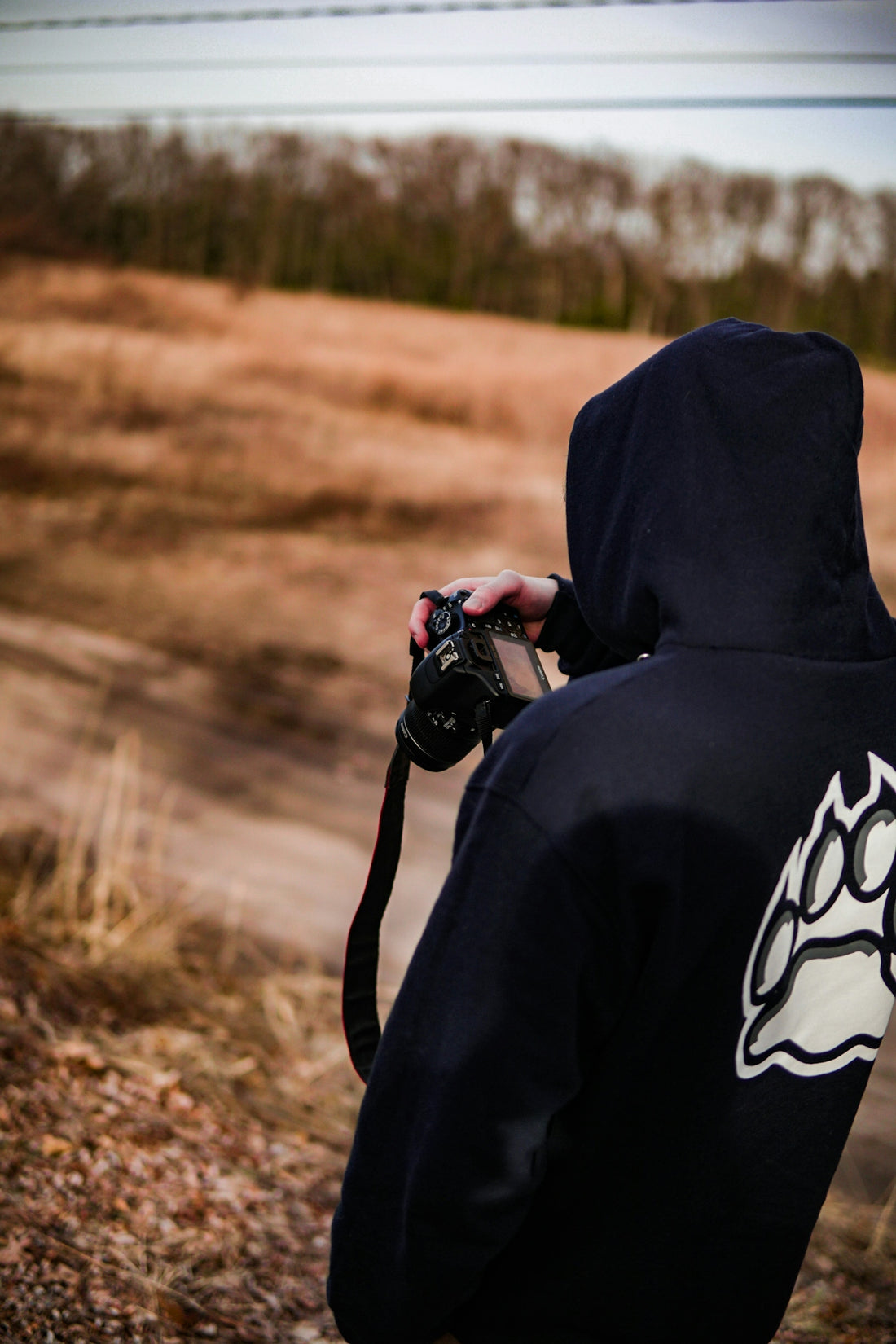 person in black hoodie holding DSLR camera