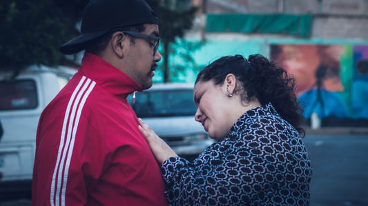 man in red jacket kissing woman in black and white knit cap