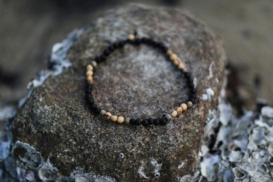 a beaded bracelet sitting on top of a rock