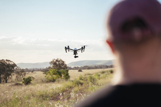 a man looking at a small plane flying in the sky