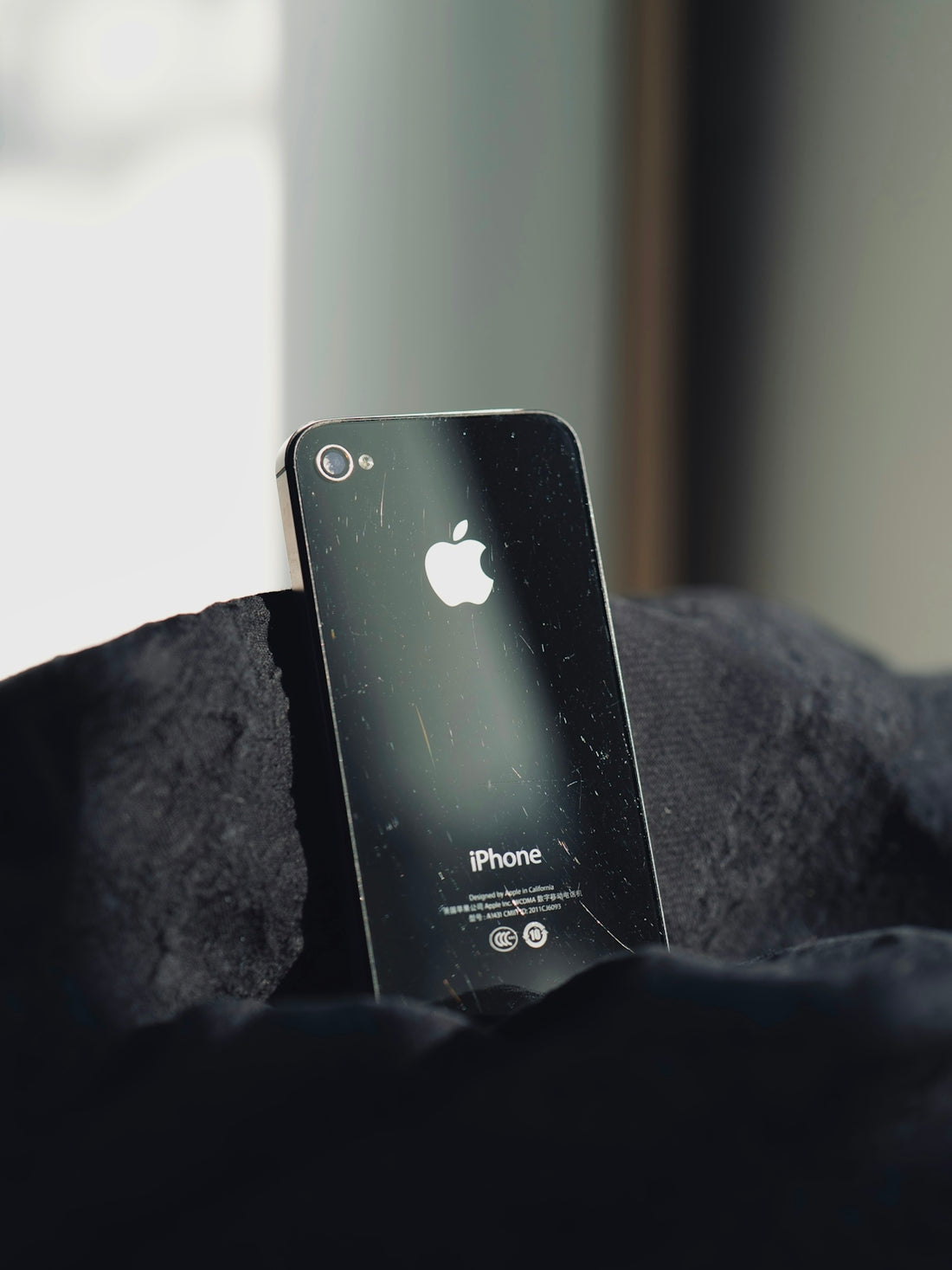 a broken iphone sitting on top of a black blanket