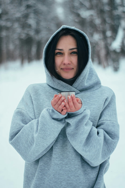 a woman standing in the snow holding a cup of coffee