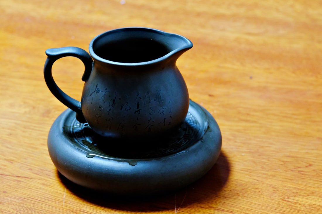 a black vase sitting on top of a wooden table
