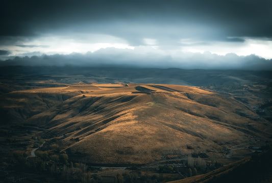 an aerial view of a hilly area under a cloudy sky
