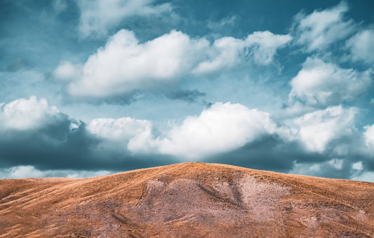 a hill covered in dirt under a cloudy sky