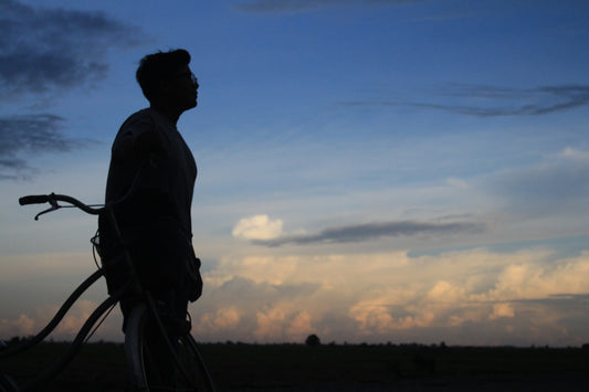 A man standing next to a bike in a field