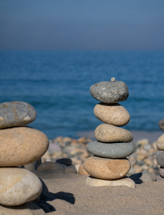 Stone stacks stand on a sandy beach with the sea.