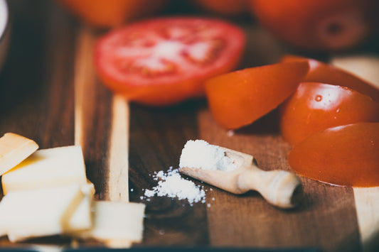 Tomatoes, cheese, and salt on a wooden board.