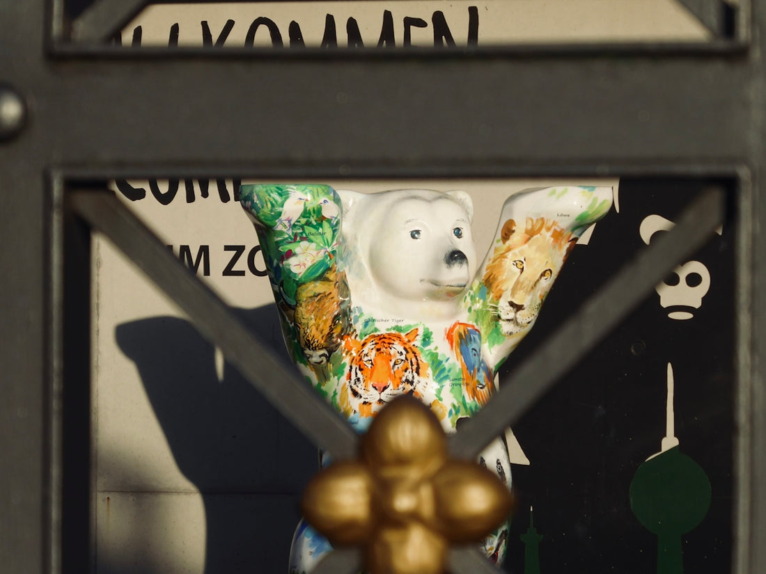 A colorful bear statue is behind a metal gate.
