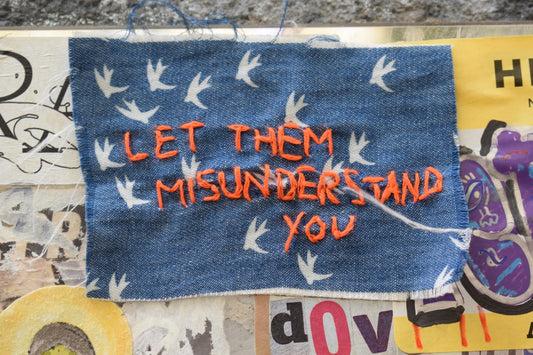 Let them misunderstand you, embroidered on fabric.