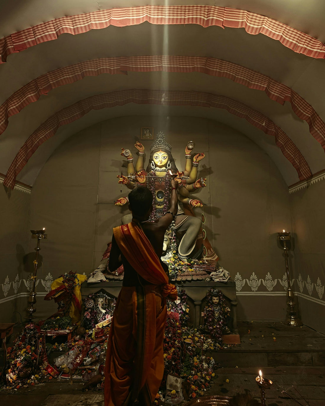 Man in orange cloth facing durga idol during worship