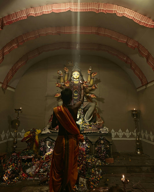 Man in orange cloth facing durga idol during worship