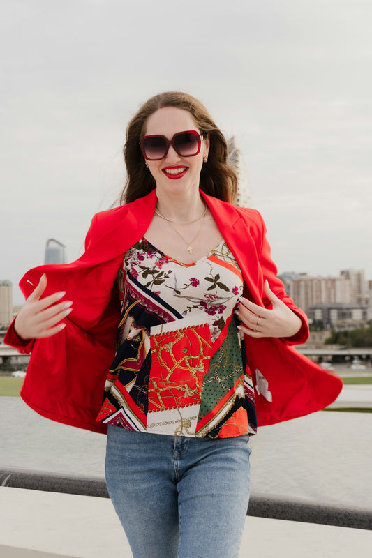 Woman in red blazer and patterned top smiles.