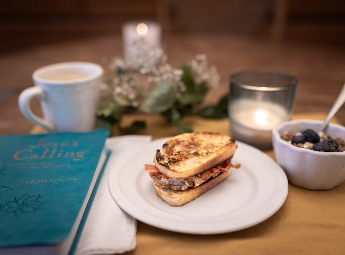 A breakfast sandwich with coffee and a book.